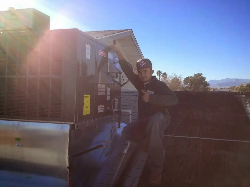 HVAC technician performing Heat Pump Repair on a rooftop unit in Wixom